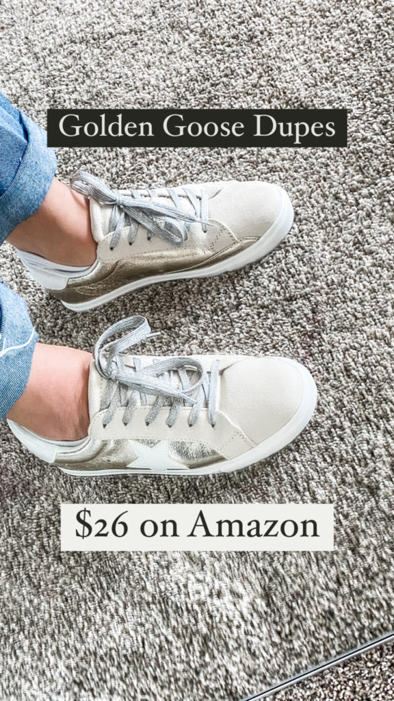 Photo shows two sneakers with silver laces and gold accents on a woman's feet. The text says Golden Goose dupes for $26 on Amazon. 