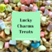It's a large picture of Lucky Charms cereal pieces - there are purple moons, rainbows, red stars, and others that make up the background image. In the center of the photo, there is a green square that states 'Lucky Charms Treats' in bold black letters. Within the green box, there is a line at the bottom that says "HoldingMoonbeams.com" This image is used as an blog graphic to visually show what the rest of the post is about which is a Lucky Charms Treats recipe and directions.